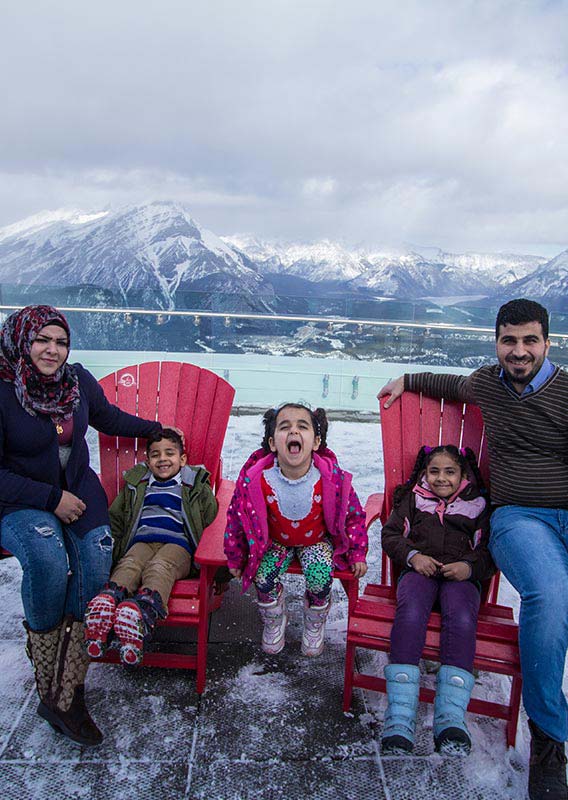 Family sit on the observation deck at the Banff Gondola summit.