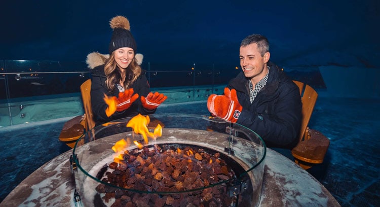 Guests warming up by the firepit at the top of Sulphur Mountain