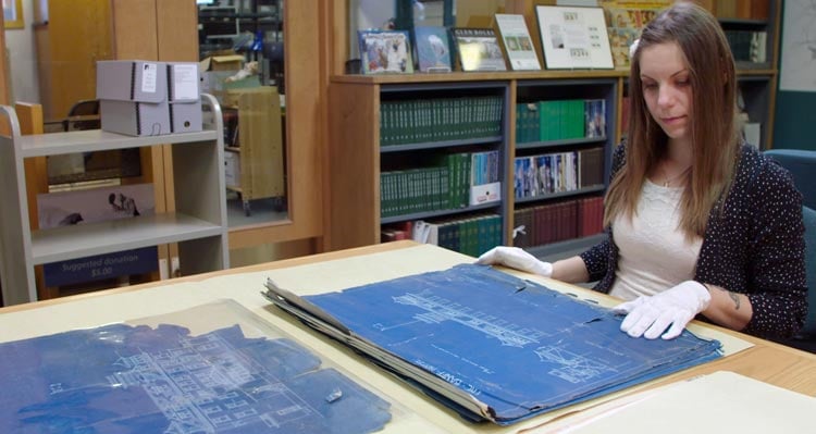 A museum researcher looks at historic blueprints in the Whyte Museum archives.