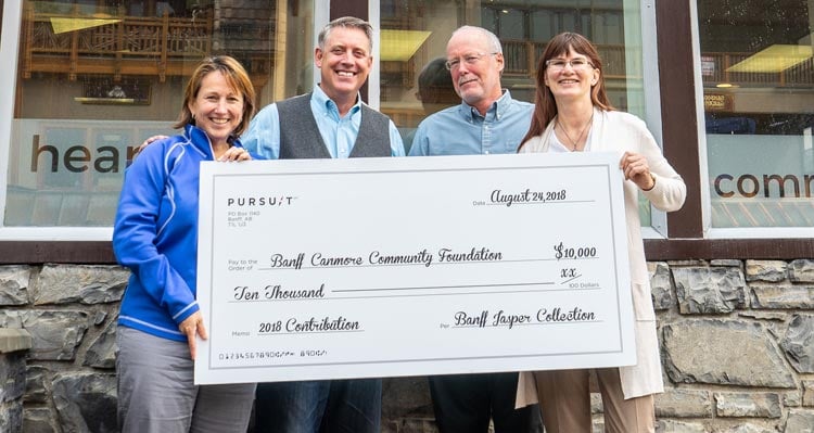 Four people hold a large cheque showing Pursuit's contribution to the Banff-Canmore Community Foundation