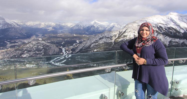 A woman leans against the railing at the Banff Gondola summit, overlooking Banff.