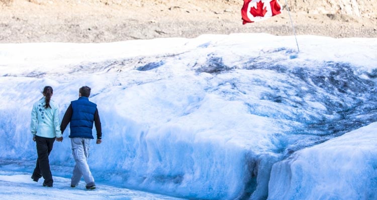 Two people walk along a glacier.
