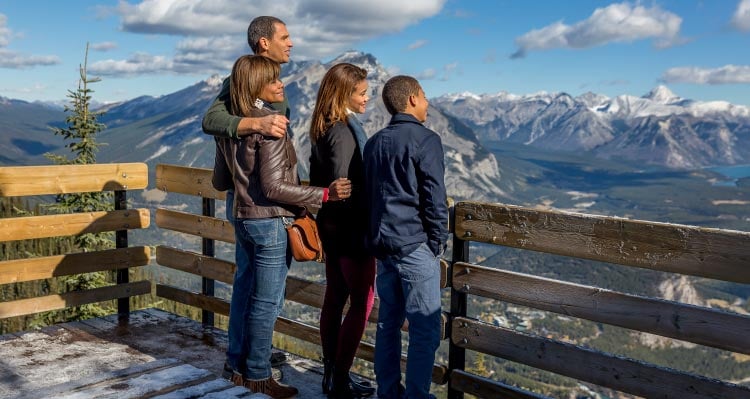 A family stands at an lookout point above mountains.