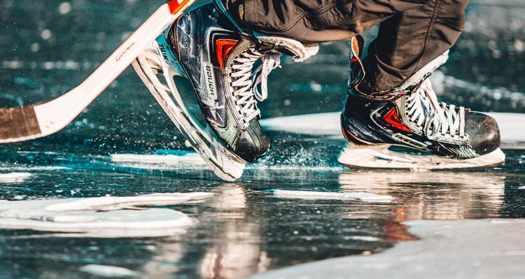 A close view of hockey skates and stick across a frozen lake.