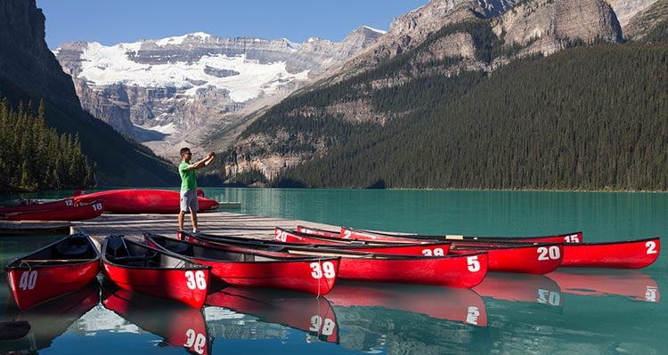 A person takes a photo from a dock with red canoes.