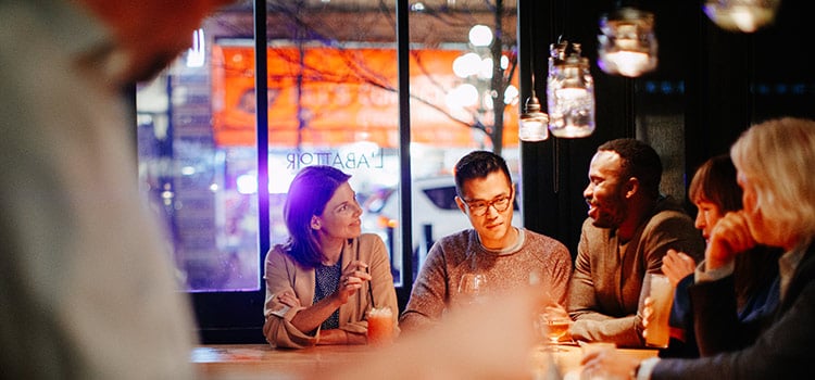 three people sit at a bar and converse
