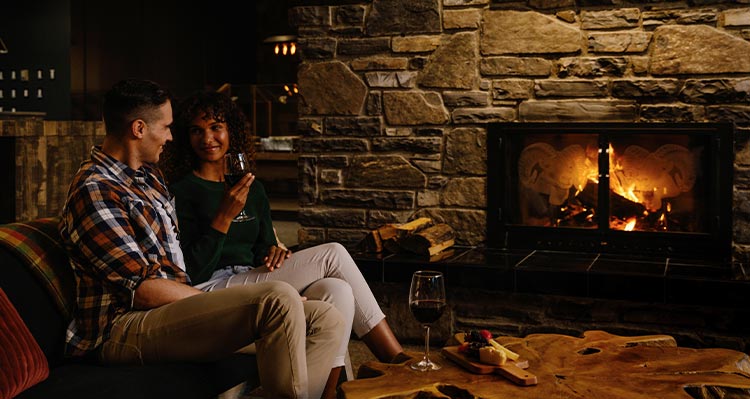 Two people sit at a fireplace.