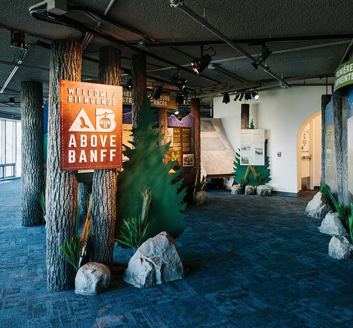 The entrance to the Above Banff Interpretive Centre posted on tree, surrounded by rocks and educational displays