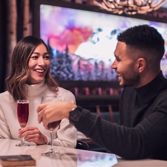 Two people sit at a restaurant bar, having drinks.