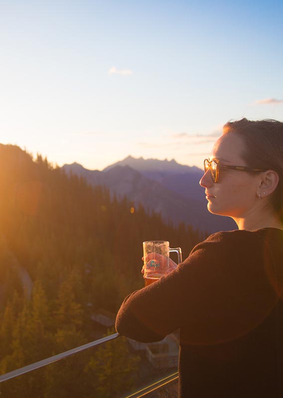 A woman looks out from a patio across a mountain landscape.