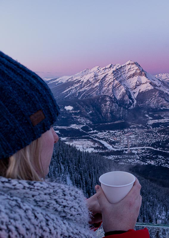 A person stands at a mountaintop viewpoint above a small town.