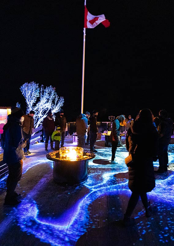 Group of people at Nightrise at night, lights on the ground and a Canadian flag are seen.