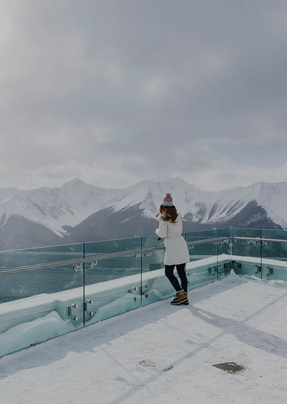 A woman in a white jacket stands alone at the Gondola lookout in winter