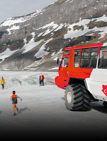 A family runs across a field of ice next to a large Ice Explorer.