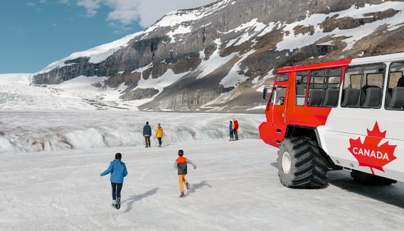 Kids run across the Athabasca glacier towards parents alongside a large Ice Explorer vehicle