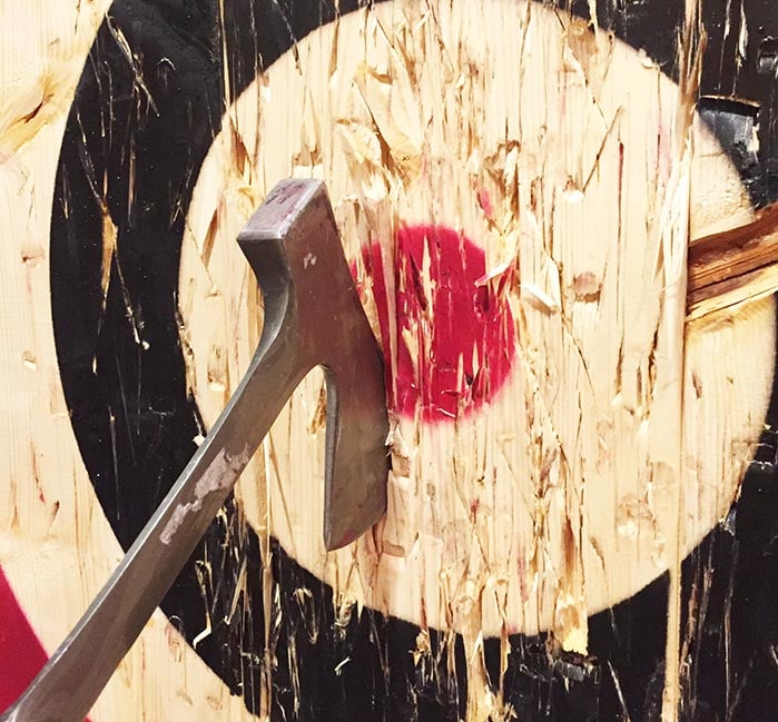 An axe embedded into a wooden bullseye mark.