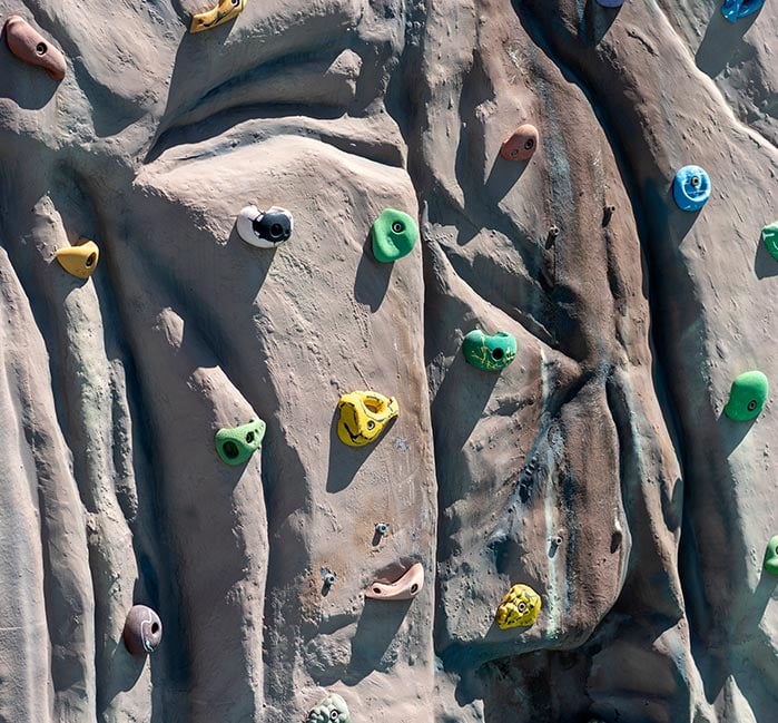 Close up shot of a climbing wall with multi-colored hand holds.