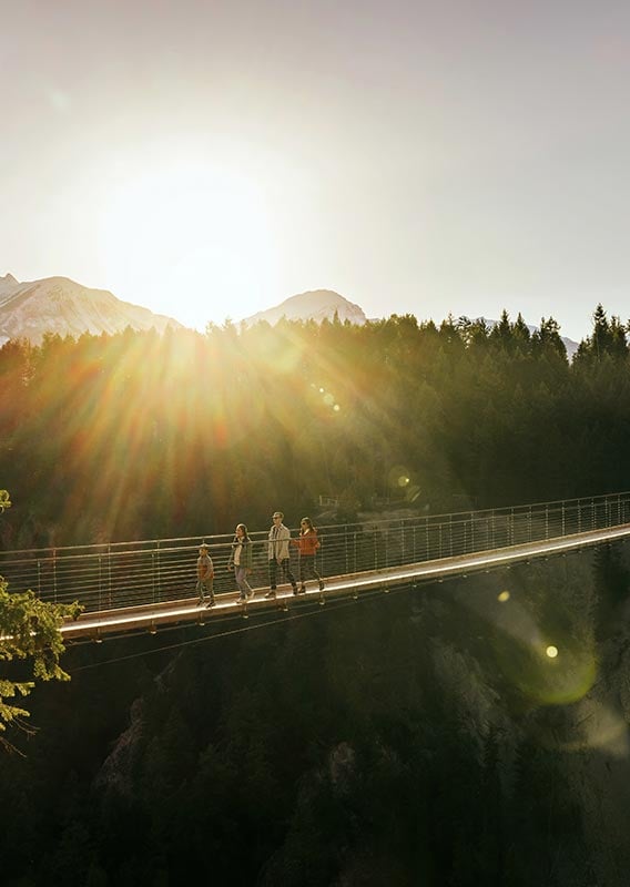 A narrow suspension footbridge stretches across a canyon.