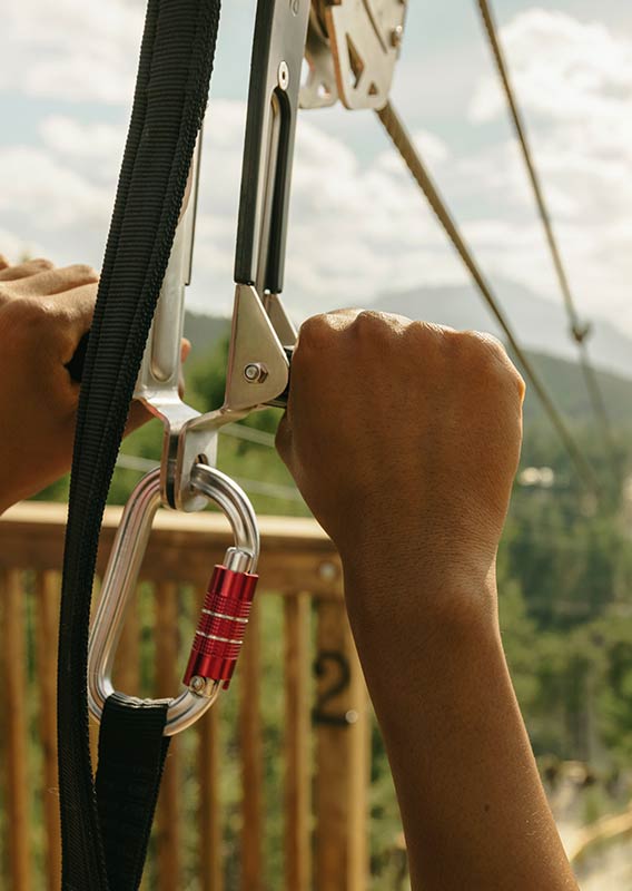 A close up shot of hands gripping the zipline handles at the top of the launch pad.