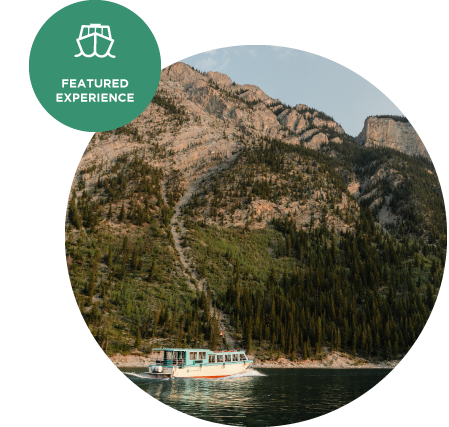 A boat cruises on a lake below a forested mountainside