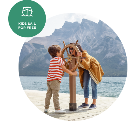 A child and mother look through a wooden boat steering wheel mountain on a lakeside dock