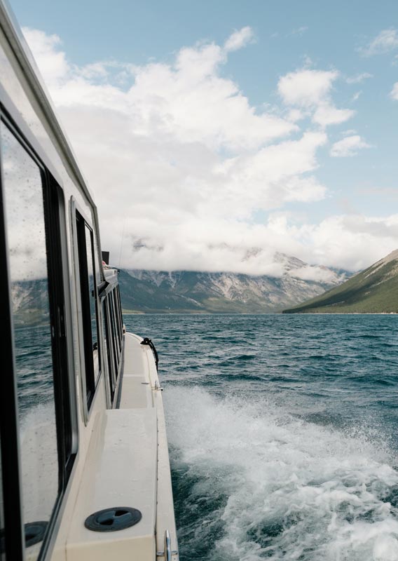 View of a blue lake surrounded by mountains from a boat