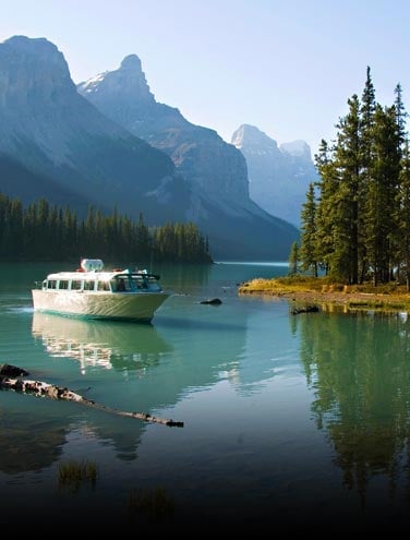 A boat approaches a lake shore, with a small treed island nearby.