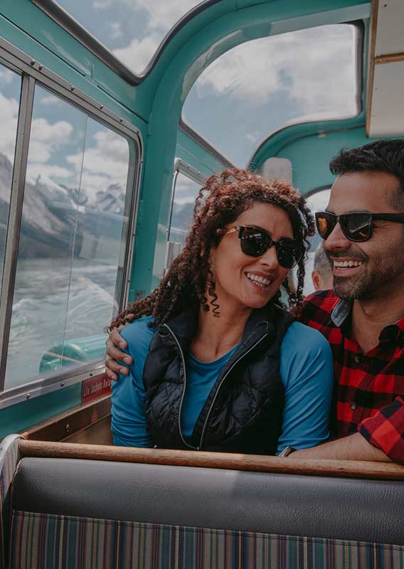 Couple sit aboard Maligne Lake Cruise boat with large windows