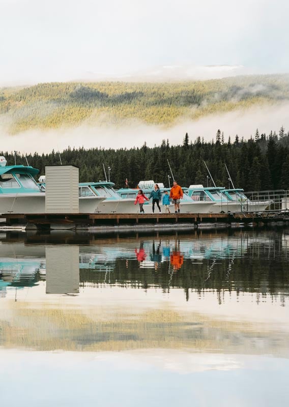 A family walks on a dock next to white and blue boats.