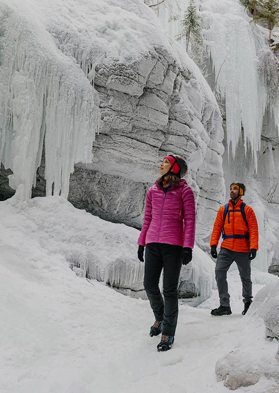 Two people walk through a frozen canyon.