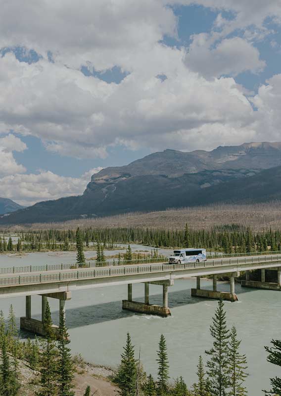 Brewster Express bus drives bridge crossing large river on a summers day