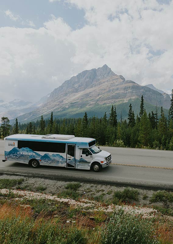Brewster Express bus travels along a road with a mountain in the background.