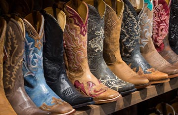 A row of cowboy boots on a store shelf.