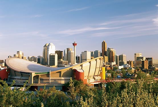 The Calgary skyline, showing a view of skyscrapers and a large arena.