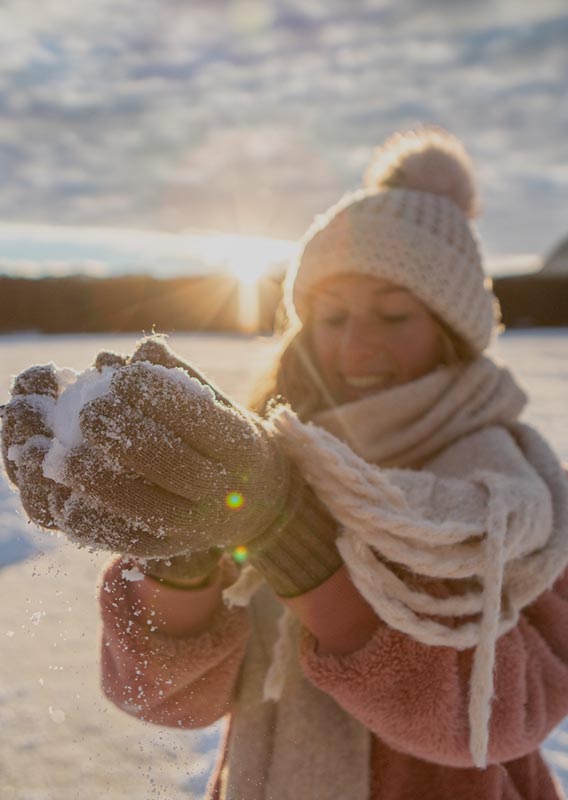 A person holds up a snowball on a field of snow.