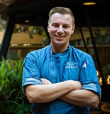 A chef stands against a grey background.