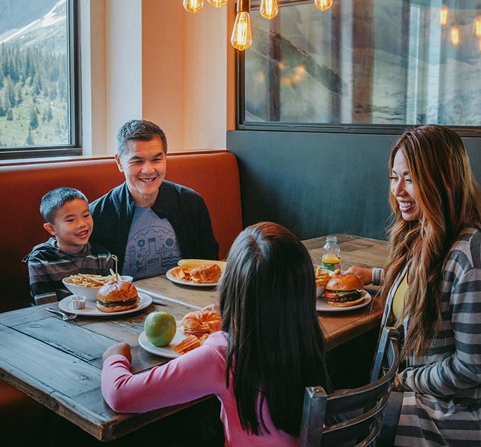 A family sits at a table by a windowside for lunch.