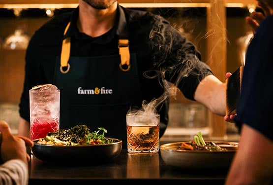 A bartender serves drinks two two people having dinner at the bar.