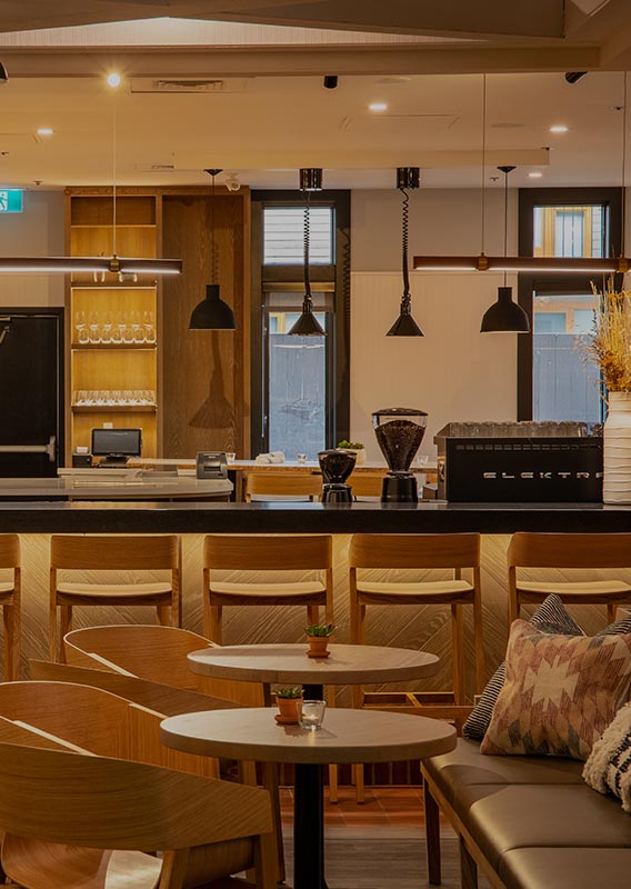 Tables, chairs and a bar in an open air dining room and kitchen