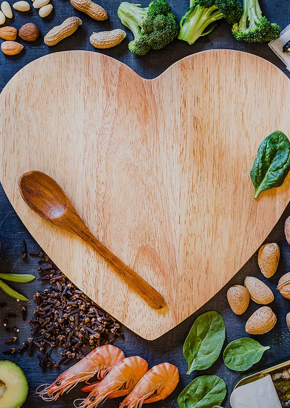 A heart-shaped wooden board surrounded by various foods