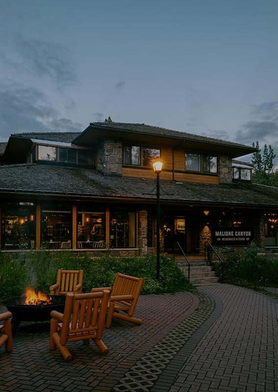 Exterior of Maligne Canyon Wilderness Kitchen with campfire and wooden chairs