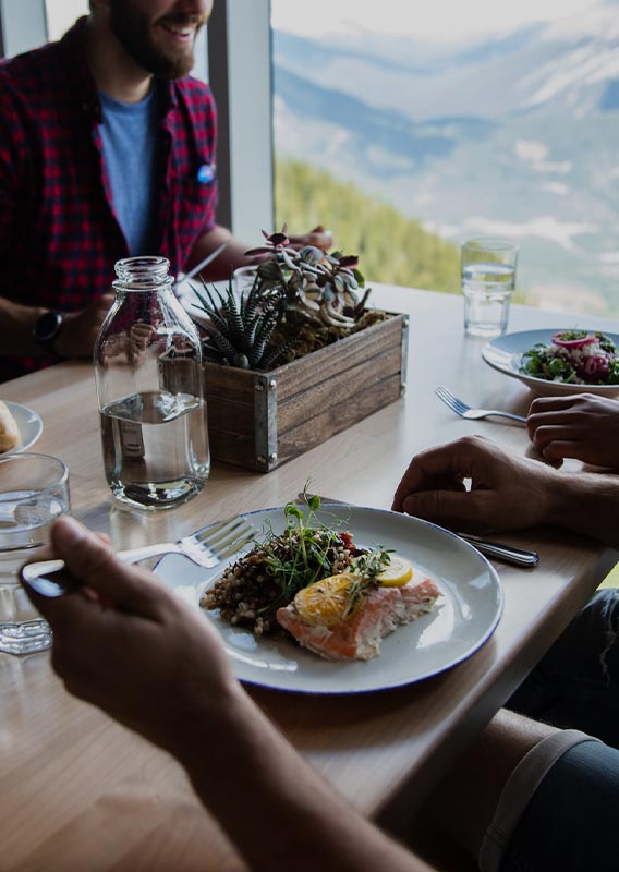 Dining tables alongside a window with a mountain view.