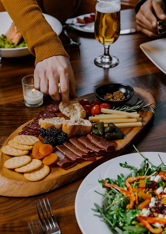 A charcuterie platter with cured meats, cheeses, and more on a dining table.