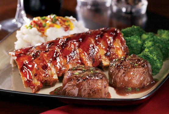 A dinner plate with steak, ribs, potatoes and vegetables.