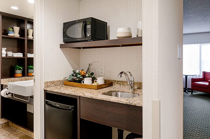 A bright kitchenette with microwave, mini fridge and sink