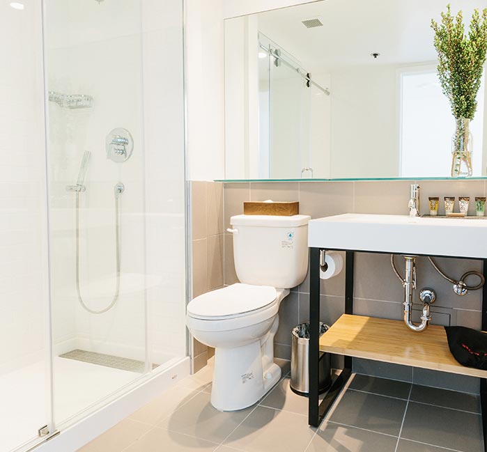 A hotel bathroom with a toilet, sink counter and glass shower.