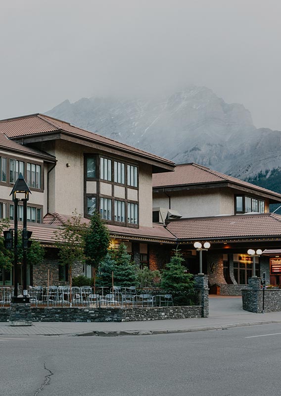 A hotel building below clouds and a tall mountain.