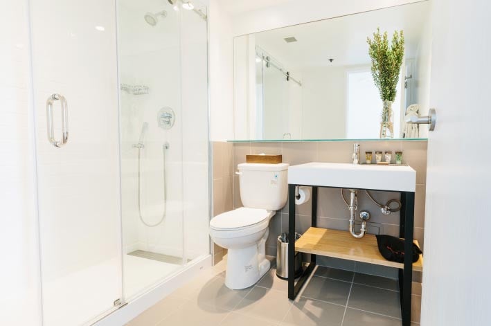 A grey tiled bathroom with a wide mirror