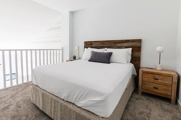 A queen bed in a hotel room loft area.