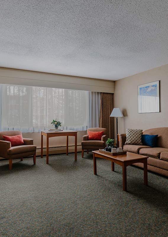 A living room space of a hotel room with couch and chairs.